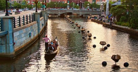 A gondola on the Providence River passes braziers for WaterFire, the famed summer fires that light up the water